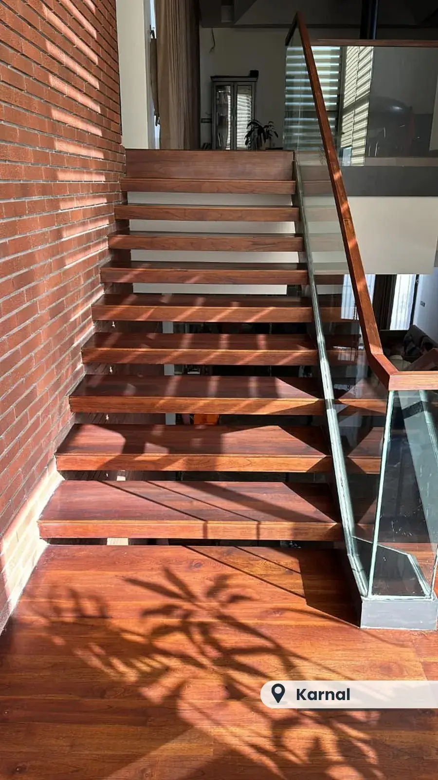 Floating wooden staircase against exposed brick, Karnal