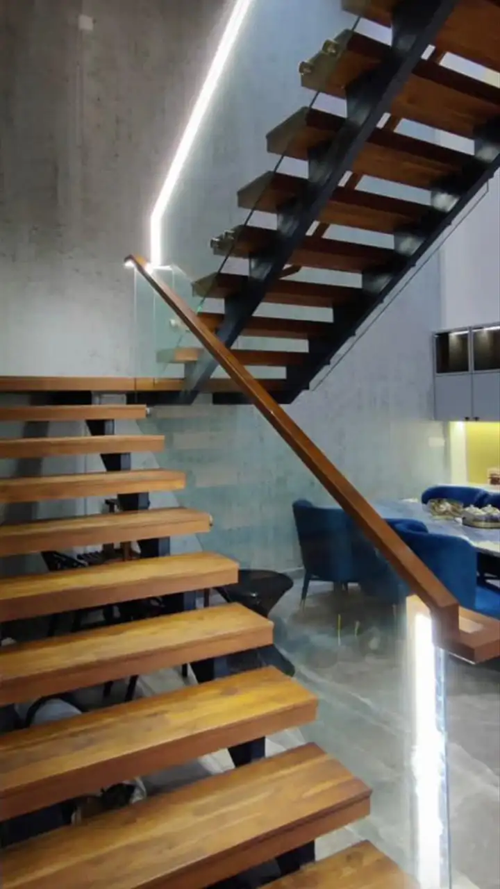 Teak treads on a black steel spine with a lit handrail